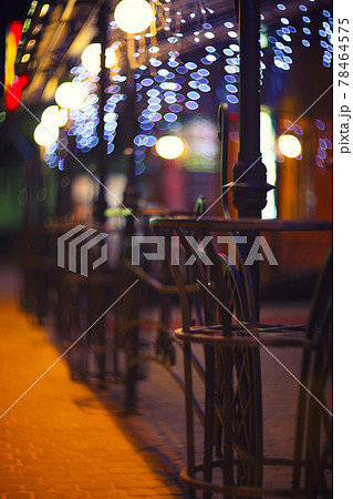 Fences and blurred night lights decorations of the bar on background. Christmas time in the city. 78464575
