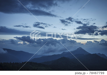 西の空に日が沈み青い光が濃く暗くなっていく夜の始まりの山並みの写真素材