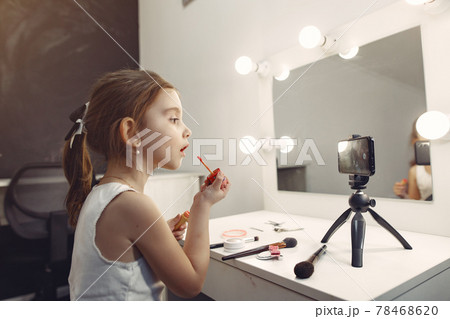 Cute little blogger with cosmetics recording video at home Cute little blogger with cosmetics recording video at home 78468620
