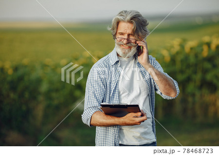 Old farmer in shirt standing on field with notebook 78468723