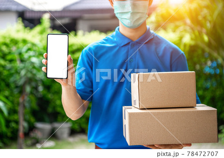 A young Asian deliveryman is delivering parcel to customer house ordered online during the outbreak of the coronavirus or Covid-19 virus. 78472707