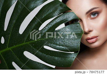 beautiful girl in palm leaves. Beautiful young woman with Make-up 78475177