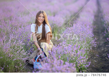 Smiling woman posing with basket in lavender field. 78476746
