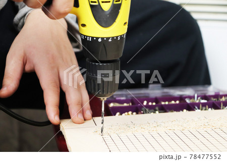 The man works as a drill in the workshop The man works as a drill in the workshop 78477552