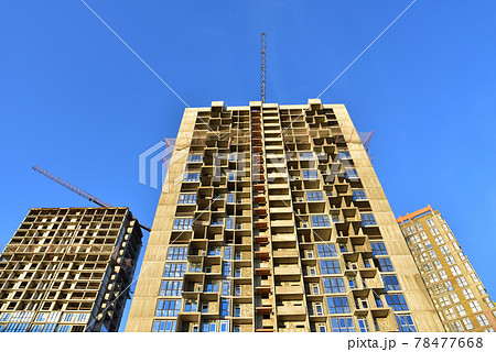Tower cranes working at construction site on blue sky background. Tower cranes working at construction site on blue sky background. 78477668