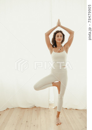 Beautiful young woman practicing yoga at home. bright room, woman is standing near the window Beautiful young woman practicing yoga at home. bright room, woman is standing near the window 78479905