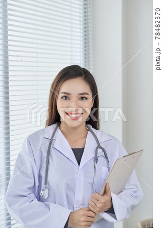 Young doctor or medic with clipboard and stethoscope standing on white background 78482370