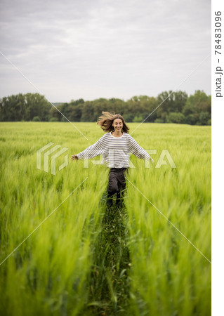 Relaxed woman standing in green field and enjoys calm nature Relaxed woman standing in green field and enjoys calm nature 78483096