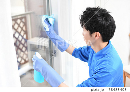 窓拭きをする清掃業のの作業服の若い男性 78483493