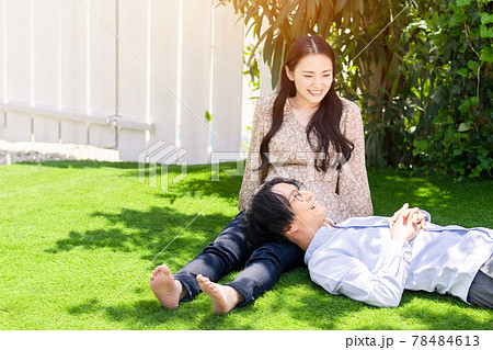 芝生で膝枕するカップル 78484613