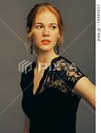 Portrait of a charming girl model in a black lace dress in the studio. The girl looks away. Vintage tinted photo. Portrait of a charming girl model in a black lace dress in the studio. The girl looks away. Vintage tinted photo. 78485017