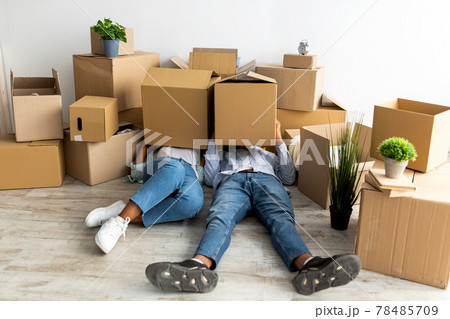 Moving day. Tired african american couple with cardboard boxes on heads, being tired in unpacking things 78485709