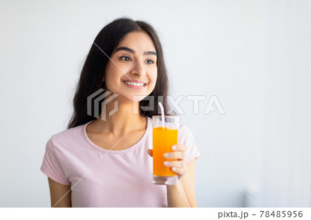 Cheerful Indian woman holding glass of refreshing fruit juice indoors. Summer detox, wellness, dieting concept Cheerful Indian woman holding glass of refreshing fruit juice indoors. Summer detox, wellness, dieting concept 78485956