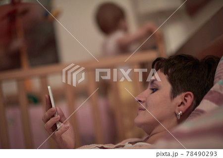 mother is using smarphone in bed while baby sleeping mother is using smarphone in bed while baby sleeping 78490293