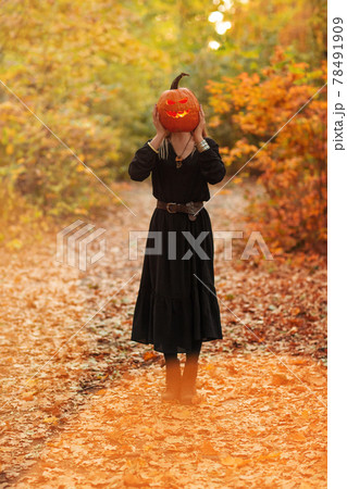 Young witch with jack o lantern in forest Young witch with jack o lantern in forest 78491909