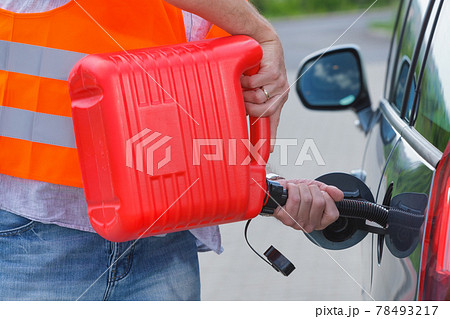 Driver fills the fuel in an empty car tank from canister. 78493217