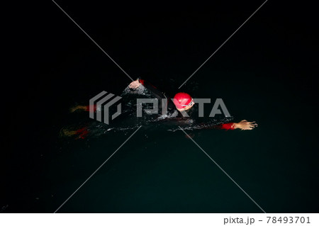 triathlon athlete swimming in dark night wearing wetsuit triathlon athlete swimming in dark night wearing wetsuit 78493701