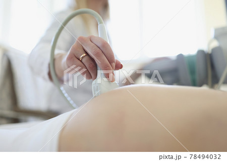 Doctor conducting ultrasound examination of fetus of pregnant woman in clinic closeup 78494032