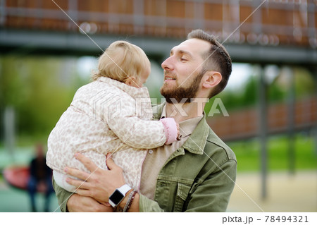 Cute toddler girl having fun on outdoor playground. Young father playing with his little daughter. Spring/summer/autumn active leisure for family with kids. 78494321