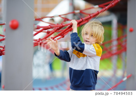 Cute preschooler boy having fun on outdoor playground. Spring/summer/autumn active sport leisure for kids. Activity for children. Equipment of entertainment park for kids. 78494503