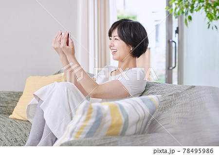 ソファでスマホを見る若い女性 ソファでスマホを見る若い女性 78495986