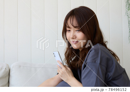 リビングでスマホを見る女性 78496152