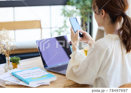 デスクでスマホを見る女性 デスクでスマホを見る女性 78497697