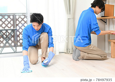 部屋で掃除をする清掃業の作業服の複数の若い男性 部屋で掃除をする清掃業の作業服の複数の若い男性 78497935