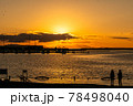 太陽が沈む夕景の波止場に佇む人影と遠景 78498040