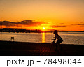 太陽が沈む夕景の波止場に佇む人影と遠景 78498044