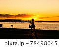 太陽が沈む夕景の波止場に佇む人影と遠景 78498045