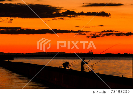 太陽が沈む夕景と遠景の釣り人 78498239