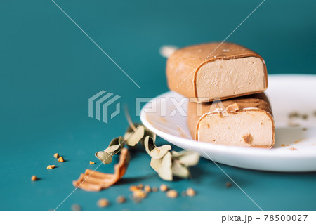 Chocolate Popsicles cut with filling lying on top of each other and white plate on cian background Chocolate Popsicles cut with filling lying on top of each other and white plate on cian background 78500027