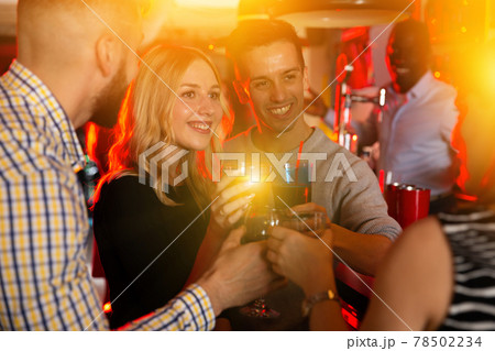 Young positive cheerful people with cocktails having fun at nightclub Young positive cheerful people with cocktails having fun at nightclub 78502234