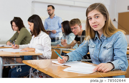 Young girl is writing test and thinking about questions at the desk Young girl is writing test and thinking about questions at the desk 78502644