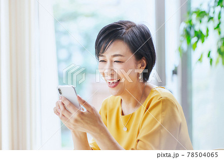 リビングでスマホを操作するミドル女性 78504065