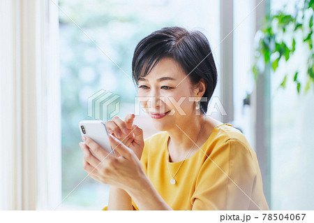 リビングでスマホを操作するミドル女性 リビングでスマホを操作するミドル女性 78504067