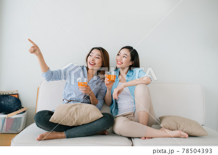Two girlfriends having a talk on the couch at home Two girlfriends having a talk on the couch at home 78504393