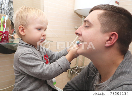Dad and son brush their teeth in the bathroom. Father Brushing Teeth to Child Dad and son brush their teeth in the bathroom. Father Brushing Teeth to Child 78505154