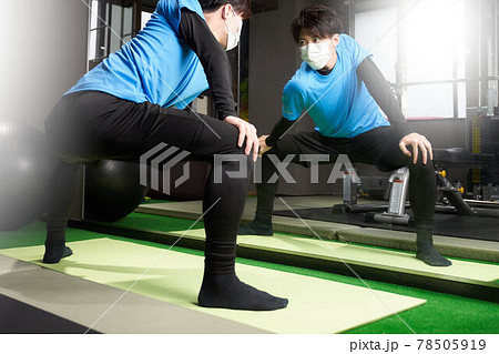 鏡の前でストレッチをするマスク姿の男性 78505919