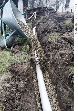 Workers carry out drainage works to drain the water around the house. 78507661