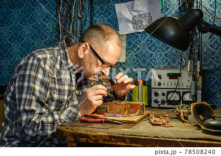 Man repairing an old radio receiver Man repairing an old radio receiver 78508240