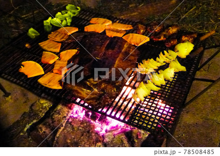 夜に炭火でバーベキューをしステーキや野菜を焼いている様子 78508485