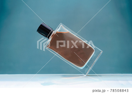 Suspended glass perfume bottle on blue background 78508843
