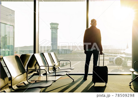 Young tourist with a suitcase standing near the window Young tourist with a suitcase standing near the window 78509298