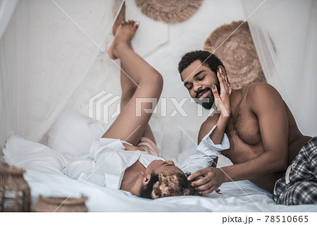 Darkskinned husband and wife lying on bed enjoying moment Darkskinned husband and wife lying on bed enjoying moment 78510665