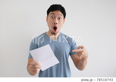 Man surprise and shocked by the letter in his hand on isolated background. Man surprise and shocked by the letter in his hand on isolated background. 78510743