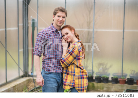 Happy woman touching confident man in greenhouse 78511083