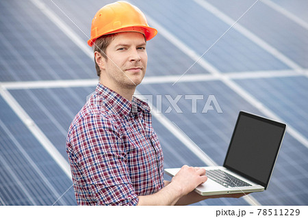 Young man in helmet working with laptop outdoors Young man in helmet working with laptop outdoors 78511229