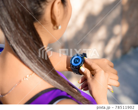 A young asian woman checks her pulse after the race. 78511902